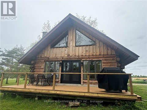 A wooden cabin with a deck and a grill.