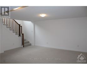 A spacious empty room with a staircase leading to the upper floor.