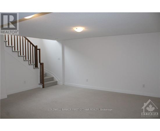 A spacious empty room with a staircase leading to the upper floor.