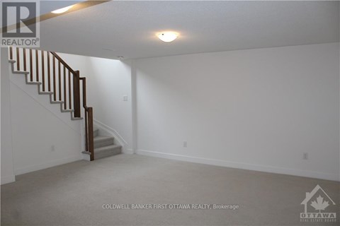 A spacious empty room with a staircase leading to the upper floor.