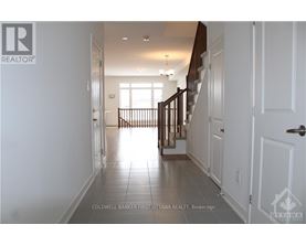 A hallway with white walls and a tiled floor leads to a bright room with a window.