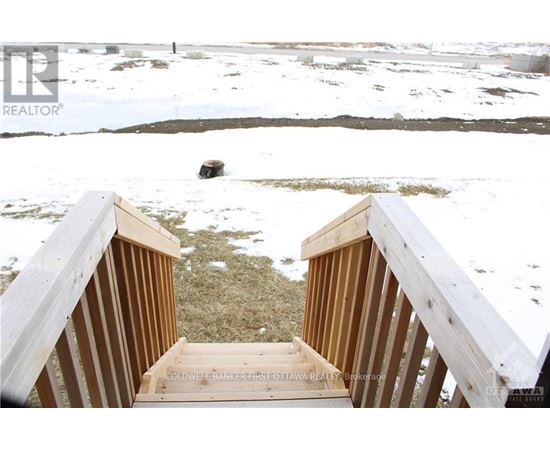 A wooden staircase leading to a grassy area with snow on the ground.