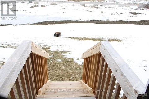 A wooden staircase leading to a grassy area with snow on the ground.