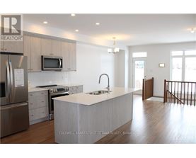 A modern kitchen with a stainless steel refrigerator, microwave, and oven.