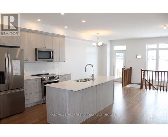 A modern kitchen with a stainless steel refrigerator, microwave, and oven.