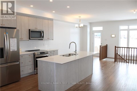 A modern kitchen with a stainless steel refrigerator, microwave, and oven.