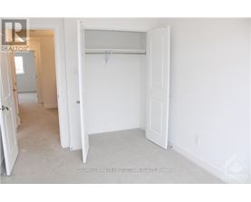 A white bedroom with a door open to a hallway.