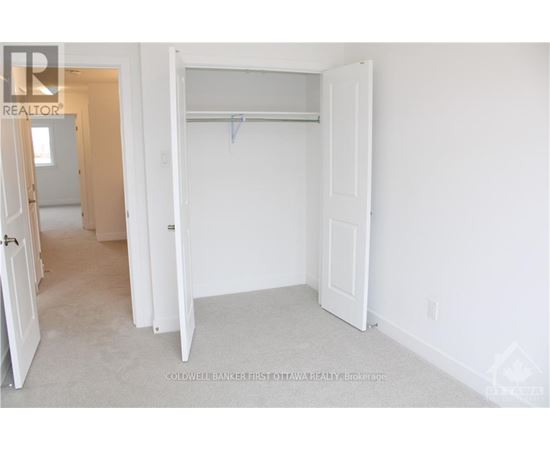 A white bedroom with a door open to a hallway.