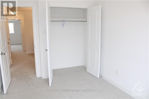 A white bedroom with a door open to a hallway.