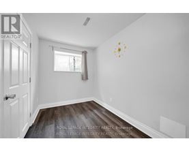 A white room with a clock on the wall and a window with blinds.
