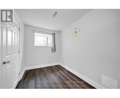 A white room with a clock on the wall and a window with blinds.