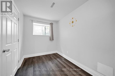 A white room with a clock on the wall and a window with blinds.