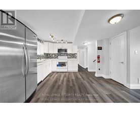 A modern kitchen with a stainless steel refrigerator and wooden flooring.