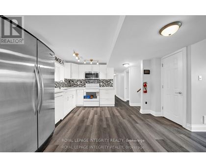 A modern kitchen with a stainless steel refrigerator and wooden flooring.