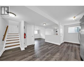 A spacious room with wooden flooring and white walls.
