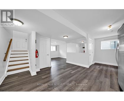 A spacious room with wooden flooring and white walls.