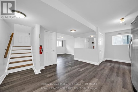 A spacious room with wooden flooring and white walls.