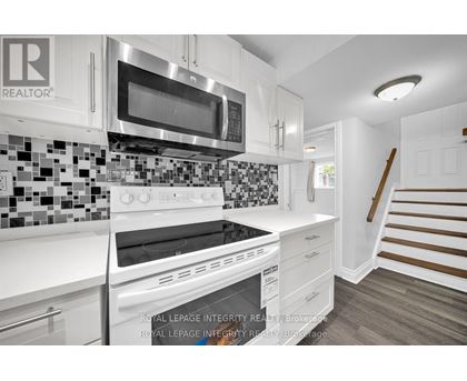 A white kitchen with a stove top oven and microwave.