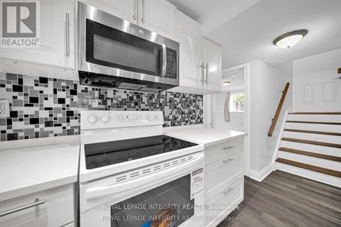 A white kitchen with a stove top oven and microwave.