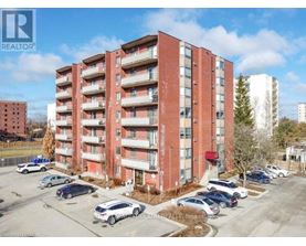 A red brick apartment building with cars parked in front.