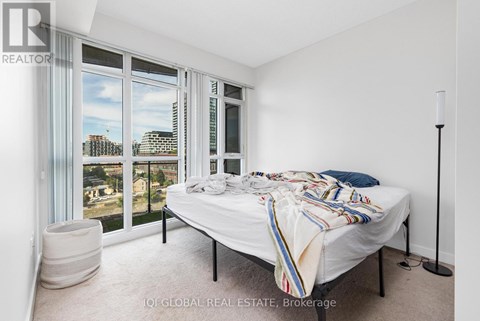 A bedroom with a large bed and a view of the city through the windows.