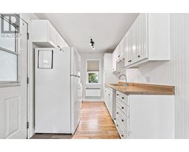 A white kitchen with wooden floors and white cabinets.
