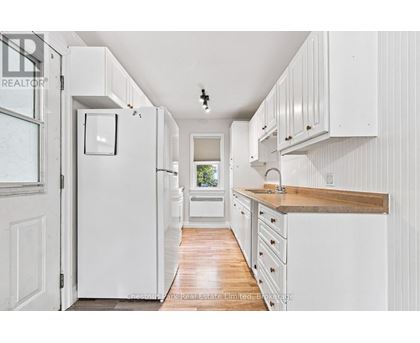 A white kitchen with wooden floors and white cabinets.