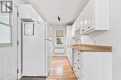 A white kitchen with wooden floors and white cabinets.