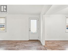 A room with a white door and a window with a view of a building outside.
