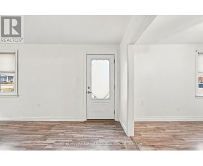 A room with a white door and a window with a view of a building outside.