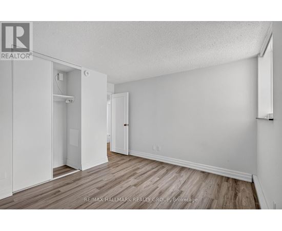 A white bedroom with wood flooring and a closet with a door open.