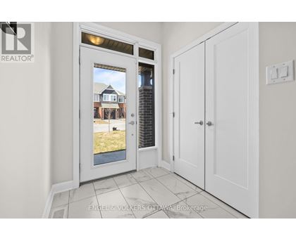 A white door with a window showing a house in the background.