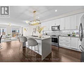 A modern kitchen with white cabinets and a wooden floor.
