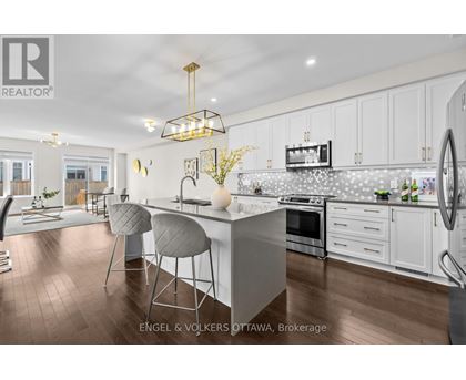 A modern kitchen with white cabinets and a wooden floor.