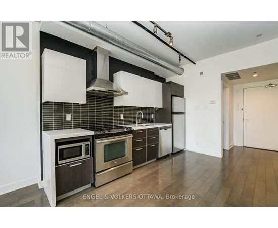 A modern kitchen with stainless steel appliances and wooden floors.