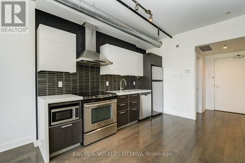 A modern kitchen with stainless steel appliances and wooden floors.