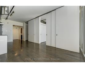 A spacious room with white walls and wooden flooring.