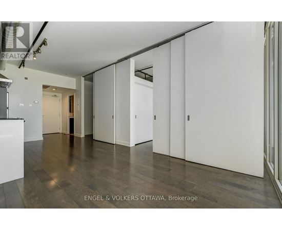 A spacious room with white walls and wooden flooring.