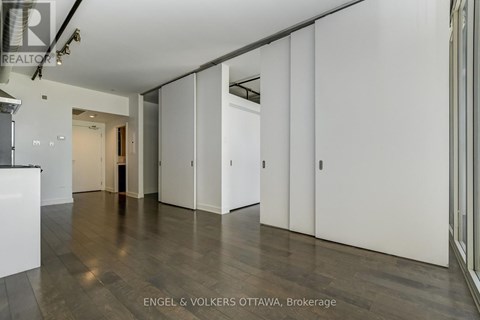 A spacious room with white walls and wooden flooring.