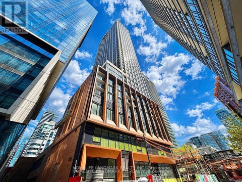 A tall building with a pointed top is surrounded by other buildings.