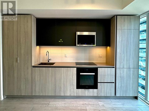 A modern kitchen with wooden cabinets and a black countertop.