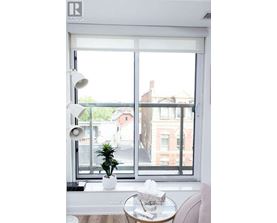 A white table with a plant on it sits in front of a window.