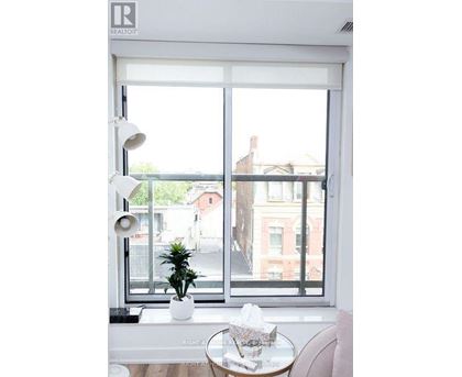 A white table with a plant on it sits in front of a window.