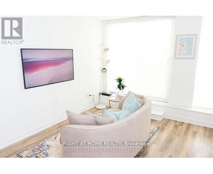 A living room with a grey couch and a painting on the wall.