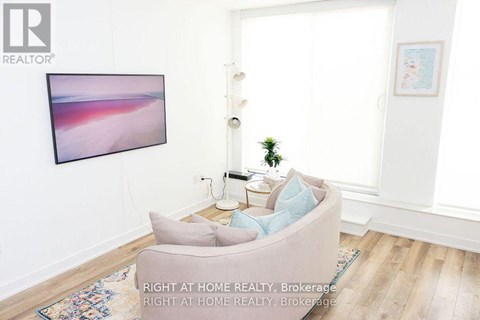 A living room with a grey couch and a painting on the wall.