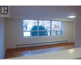 A room with a window showing a view of a building and trees outside.