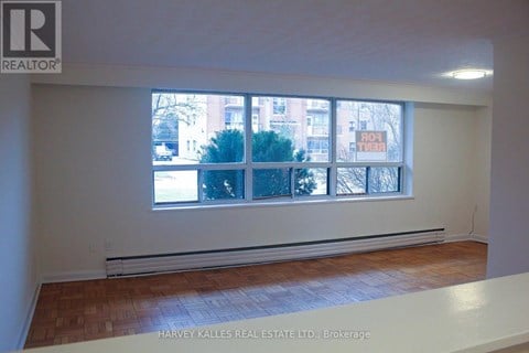 A room with a window showing a view of a building and trees outside.