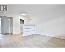 A white bedroom with a bed and a dresser.