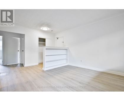 A white bedroom with a bed and a dresser.