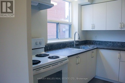 A kitchen with white cabinets and a black countertop.